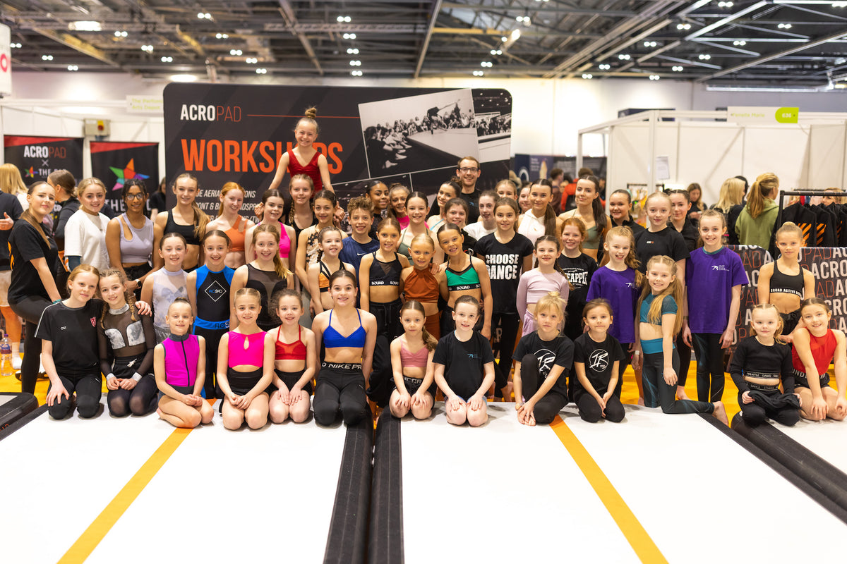 A large group of young dancers and gymnasts at an AcroPAD workshop, sitting on an AcroPAD AirFloor