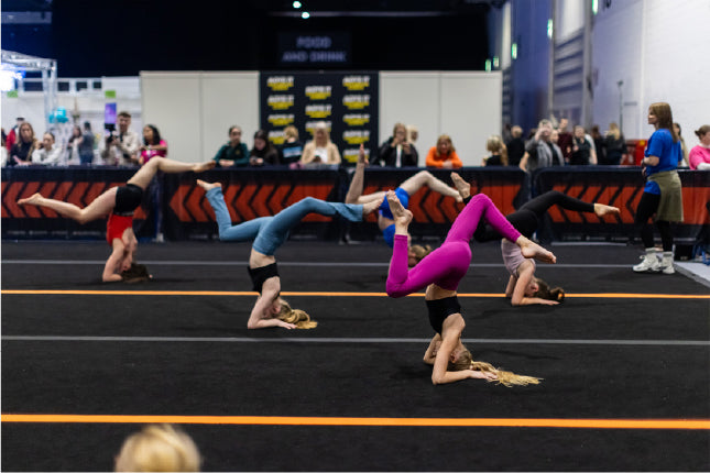 Acrobats performing on a trampoline at an indoor event 