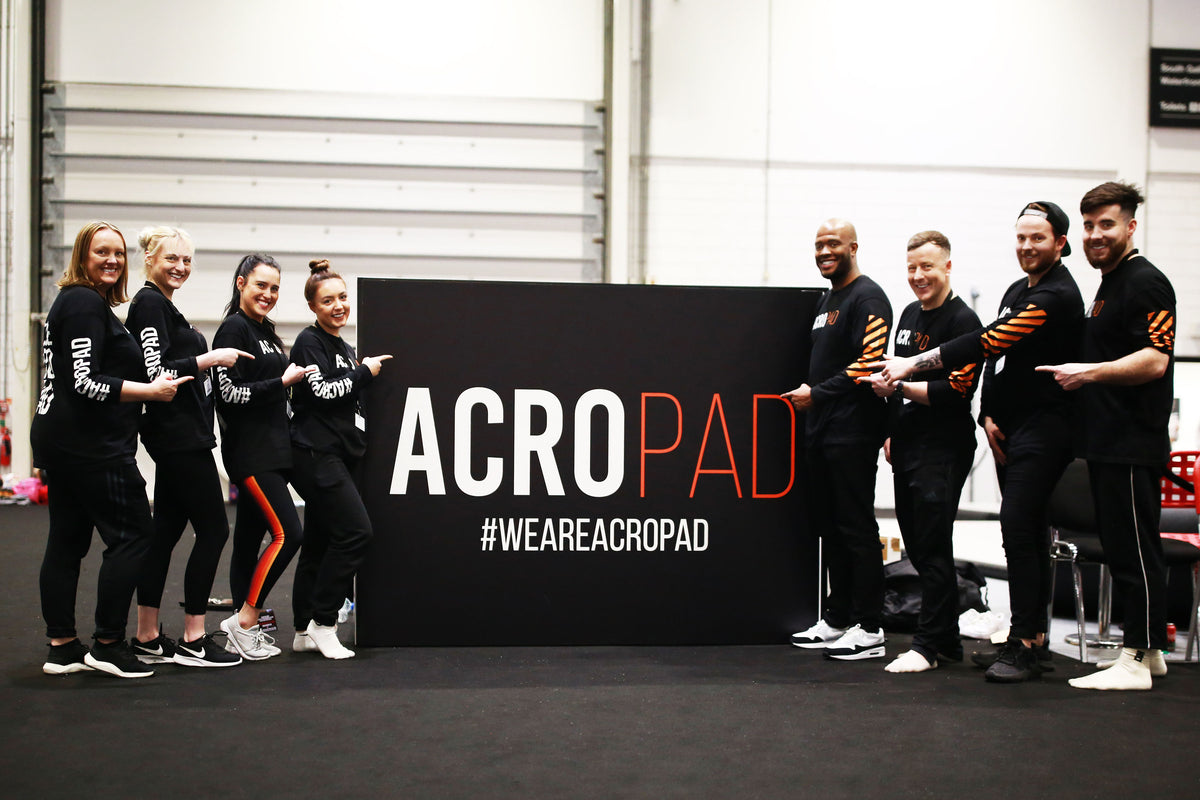 The AcroPAD team standing either side of an AcroPAD #WEAREACROPAD sign